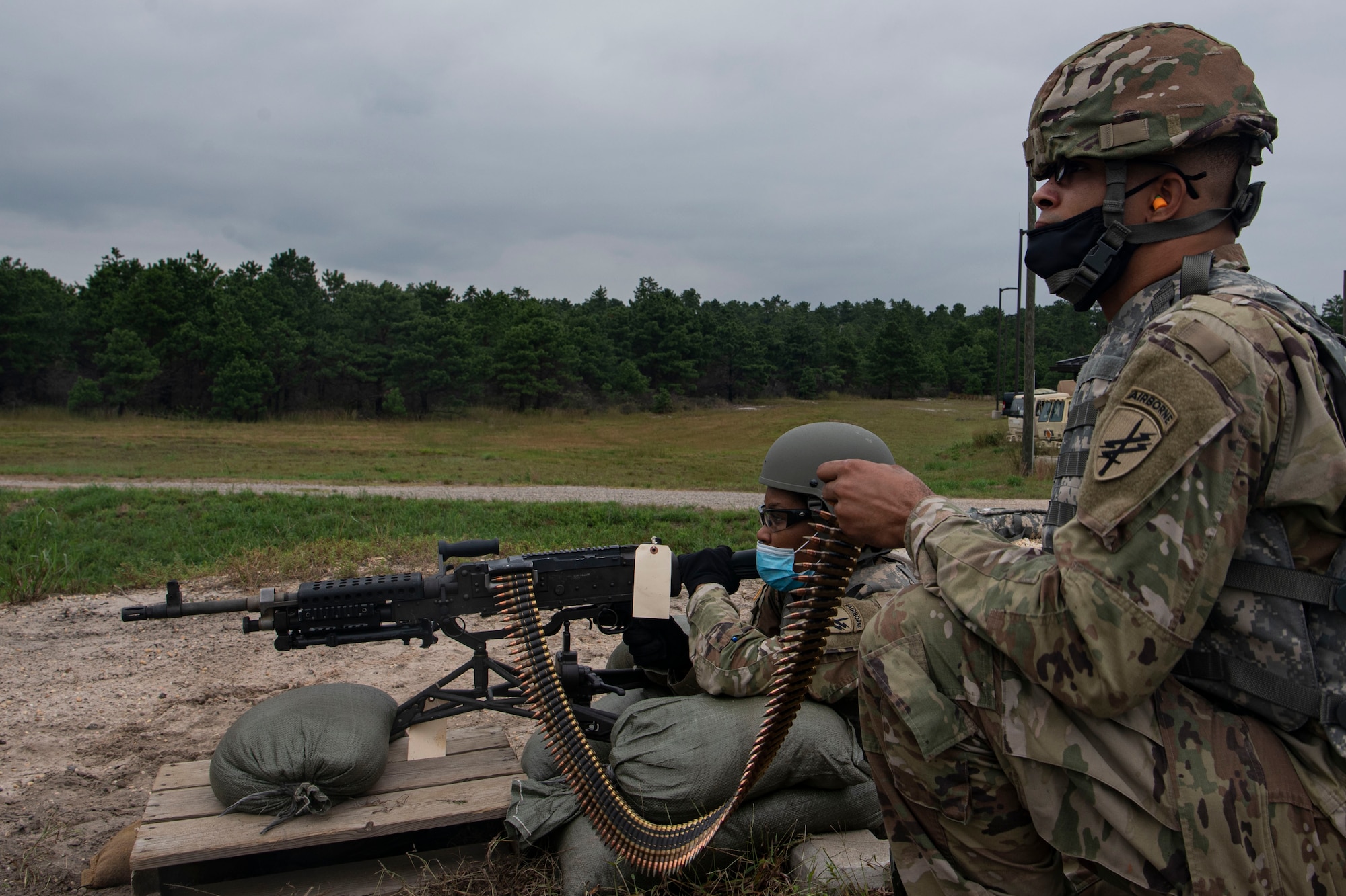 Photo of a soldier holding ammunition for another soldier.