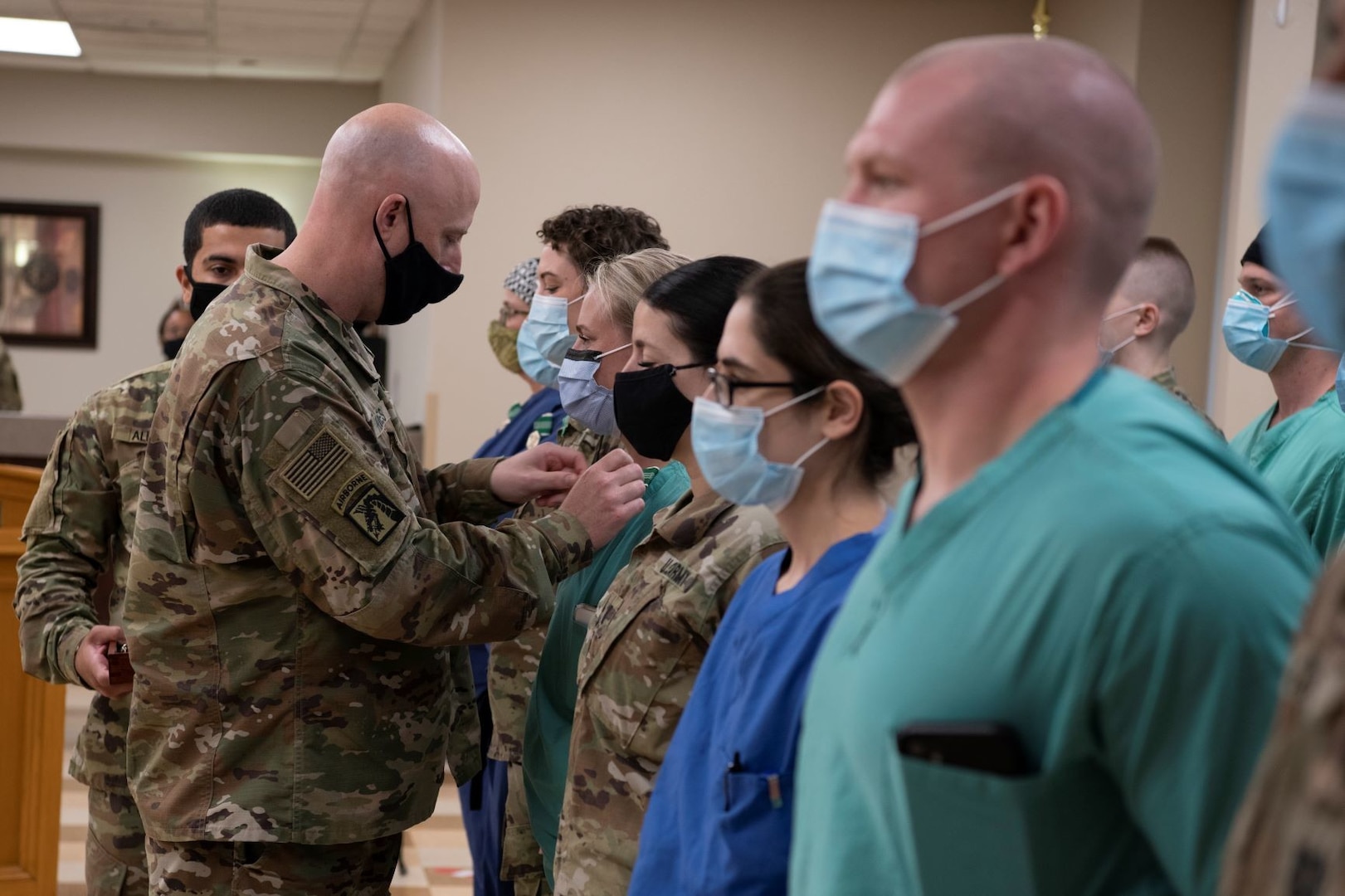 A military commander pins an award on a Soldier in a medical center.