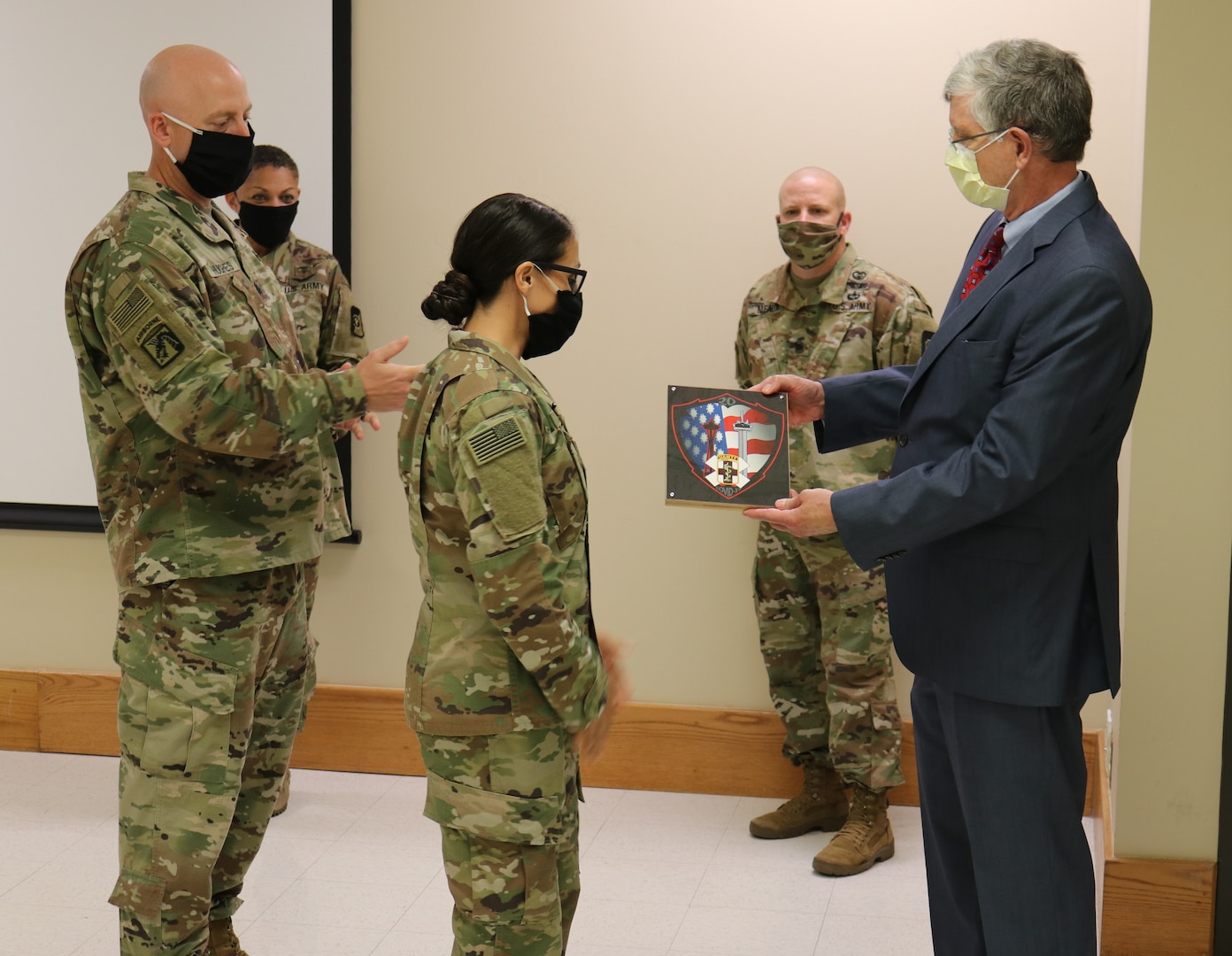 Two Soldiers presenting a plaque to a man.