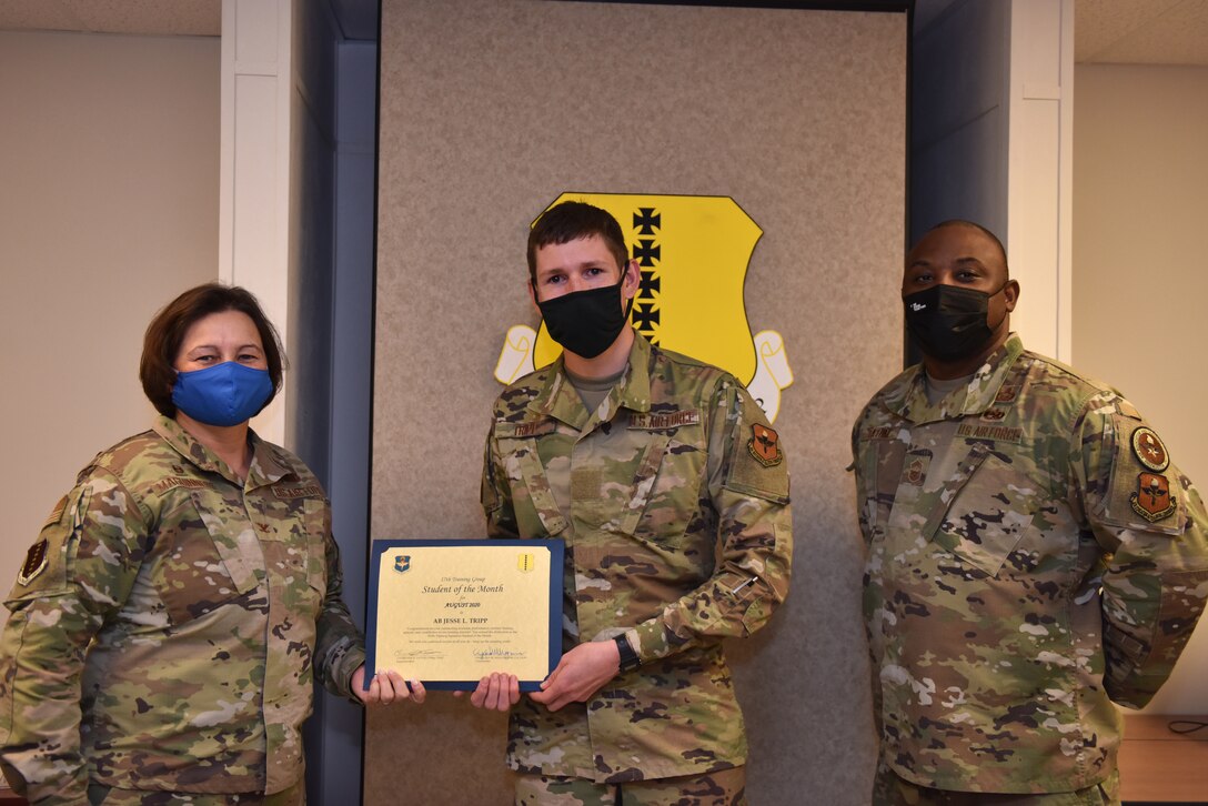 U.S. Air Force Col. Angelina Maguinness, 17th Training Group commander, and Chief Master Sgt. Charmane Tatum, 17th TRG superintendent, present Airman Jesse Tripp, 315th Training Squadron student, with his award. The 315th TRS’ mission is to train, educate and mentor our future intelligence, surveillance, and reconnaissance warriors through innovation. (U.S. Air Force photo by Staff Sgt. Seraiah Wolf)