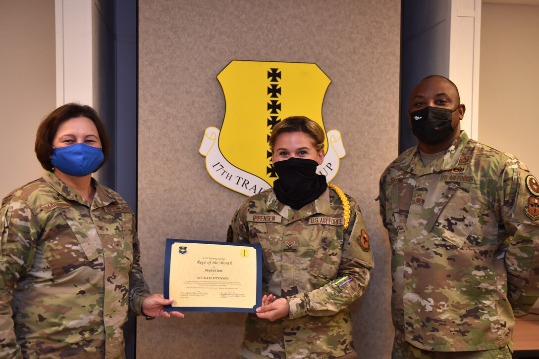 U.S. Air Force Col. Angelina Maguinness, 17th Training Group commander, and Chief Master Sgt. Charmane Tatum, 17th TRG superintendent, present Airman 1st Class Kate Ippensen, 316th Training Squadron student, with her award. Military Training Leaders present different ropes to Airmen who display exceptional qualities to lead their peers in various aspects of the training pipeline. (U.S. Air Force photo by Staff Sgt. Seraiah Wolf)