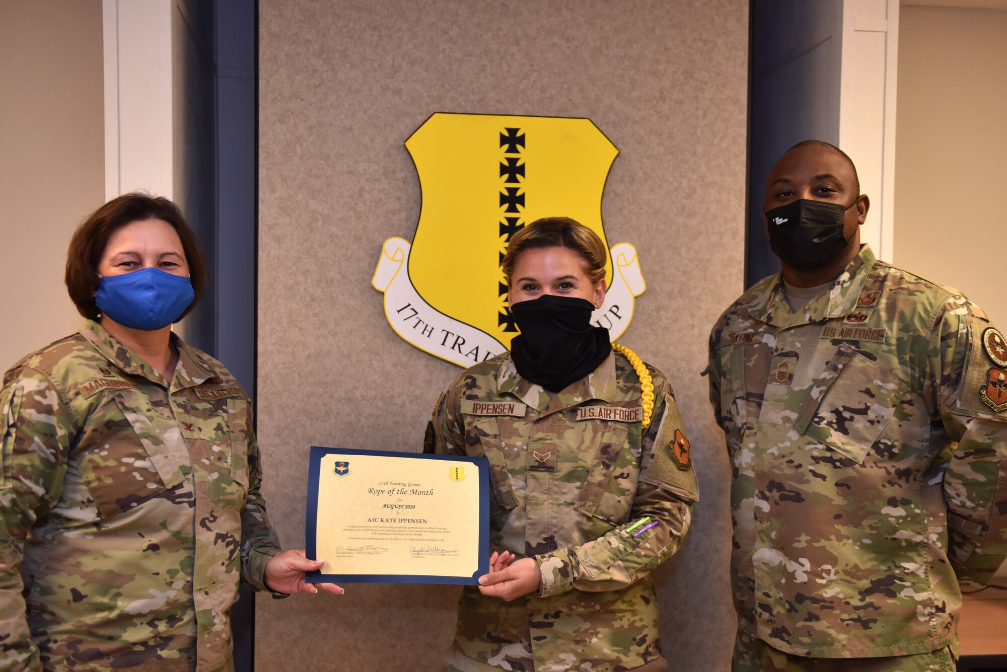 U.S. Air Force Col. Angelina Maguinness, 17th Training Group commander, and Chief Master Sgt. Charmane Tatum, 17th TRG superintendent, present Airman 1st Class Kate Ippensen, 316th Training Squadron student, with her award. Military Training Leaders present different ropes to Airmen who display exceptional qualities to lead their peers in various aspects of the training pipeline. (U.S. Air Force photo by Staff Sgt. Seraiah Wolf)