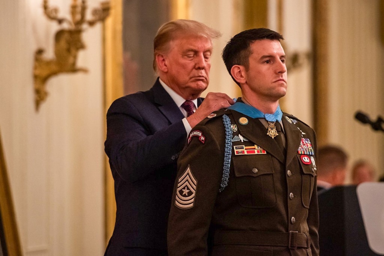 A man puts the medal of honor around the neck of another man.