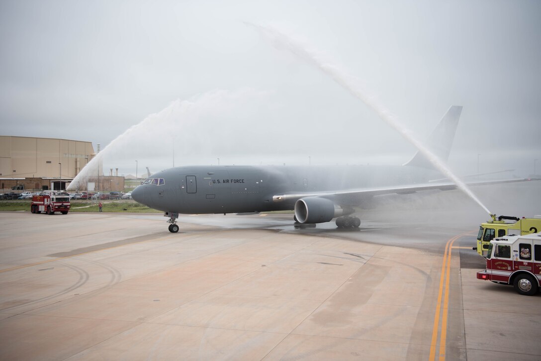 Gray airplane being sprayed by fire trucks