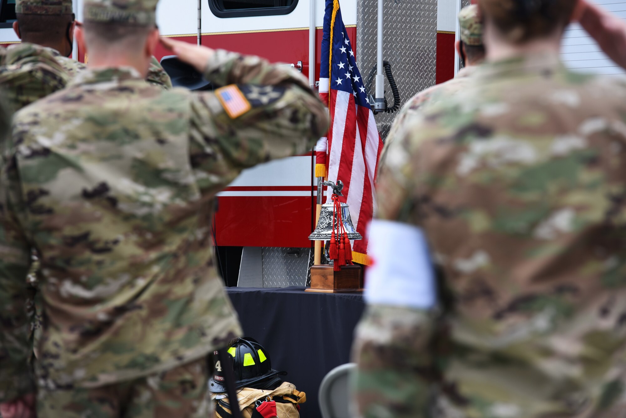 Team Osan salutes during the presentation of the colors at Osan Air Base, Republic of Korea, Sept. 11, 2020. The 51st Civil Engineer Squadron’s Fire Department rendered honors in a custom known as “striking the four fives.” The practice includes ringing a bell five times, repeated four times with a slight pause between each series. This signifies a firefighter has died in the line of duty, or an important official or personage died. (U.S. Air Force photo by Senior Airman Branden Rae)