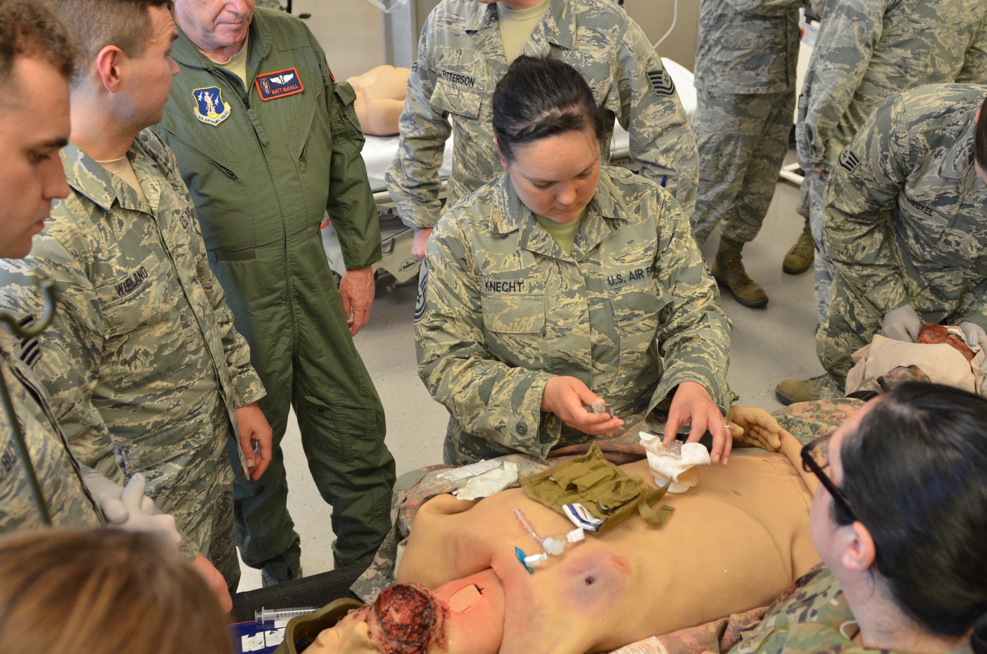 A uniformed team of Air National Guard medical technicians practice combat care on training dummies.