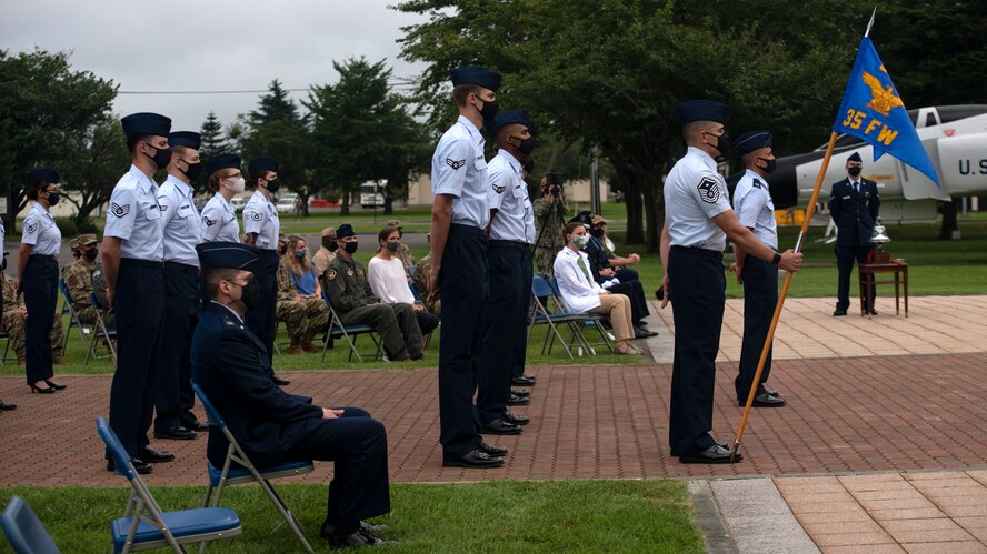 Individuals in uniform participate in an outdoor ceremony