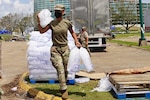 Louisiana National Guard Pfc. Reion Jones with the 1-141st Field Artillery Battalion, 256th Infantry Brigade Combat Team, hauls ice to a citizen's vehicle while working at a distribution site following Hurricane Laura in Lake Charles, Louisiana, Sept. 4, 2020.