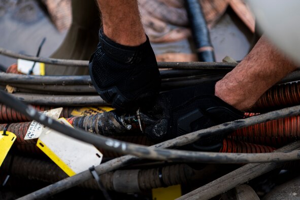 A cable antenna systems technician with the 85th Engineering Installation Squadron assigned to Keesler Air Force Base, Mississippi, cuts cable at Tyndall Air Force Base, Florida, Aug. 28, 2020. The 85th EIS is assisting the 325th Communications Squadron to move information transfer nodes from damaged buildings, which will improve network stability. (U.S. Air Force photo by Tech. Sgt. Clayton Lenhardt)