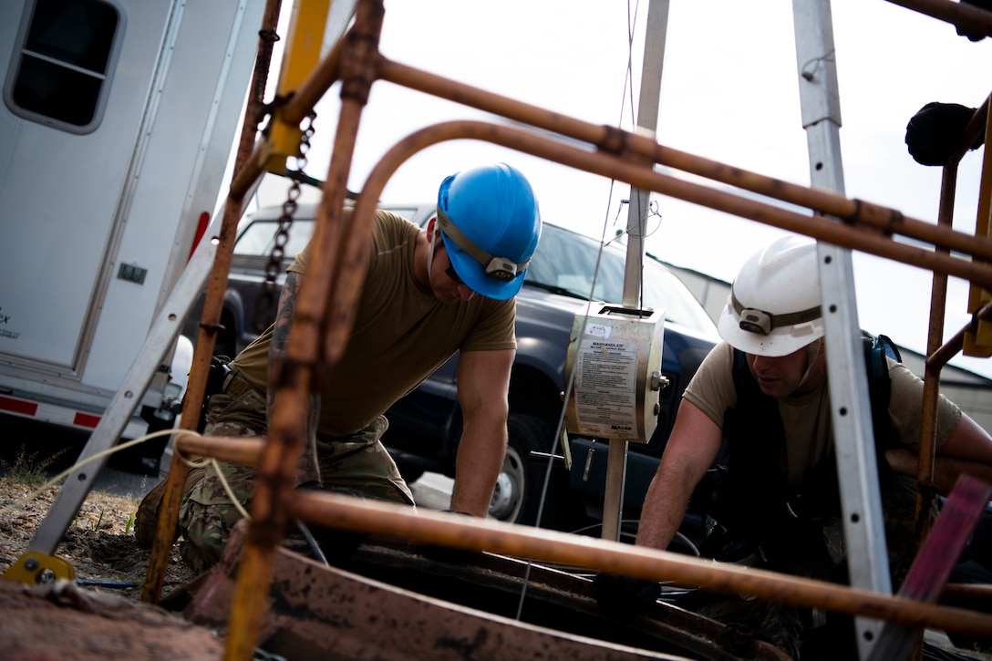U.S. Air Force Senior Airman Trent Olson and Staff Sgt. Jesse Laclair, cable antenna systems technicians with the 85th Engineering Installation Squadron assigned to Keesler Air Force Base, Mississippi, watch from above as a co-worker sorts cable at Tyndall Air Force Base, Florida, Aug. 28, 2020. The 85th EIS is assisting the 325th Communications Squadron to move information transfer nodes from damaged buildings, which will improve network stability. (U.S. Air Force photo by Tech. Sgt. Clayton Lenhardt)