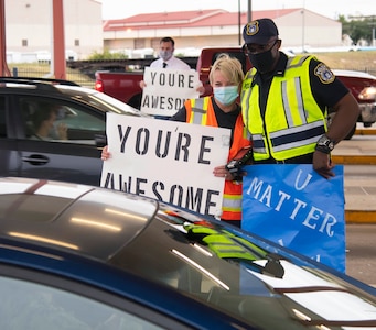 Carol Schmidt and Air Force Police Officer Lt. Steven B. Dews, both with the 502nd Security Forces Squadron, greet personnel entering the base while holding signs with positive messages in honor of World Suicide Prevention Day at the Walters Street Entry Control Point at Joint Base San Antonio-Fort Sam Houston Sept. 10.