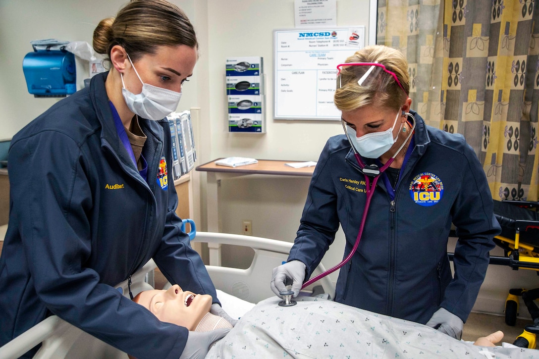 Navy sailors wearing face masks and gloves perform a code blue drill on a simulation mannequin.