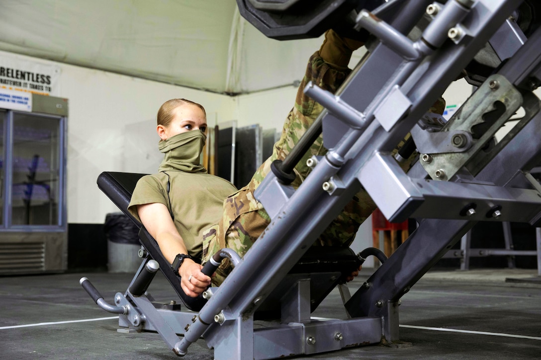 A soldier wearing a face mask works out at the MWR main fitness center