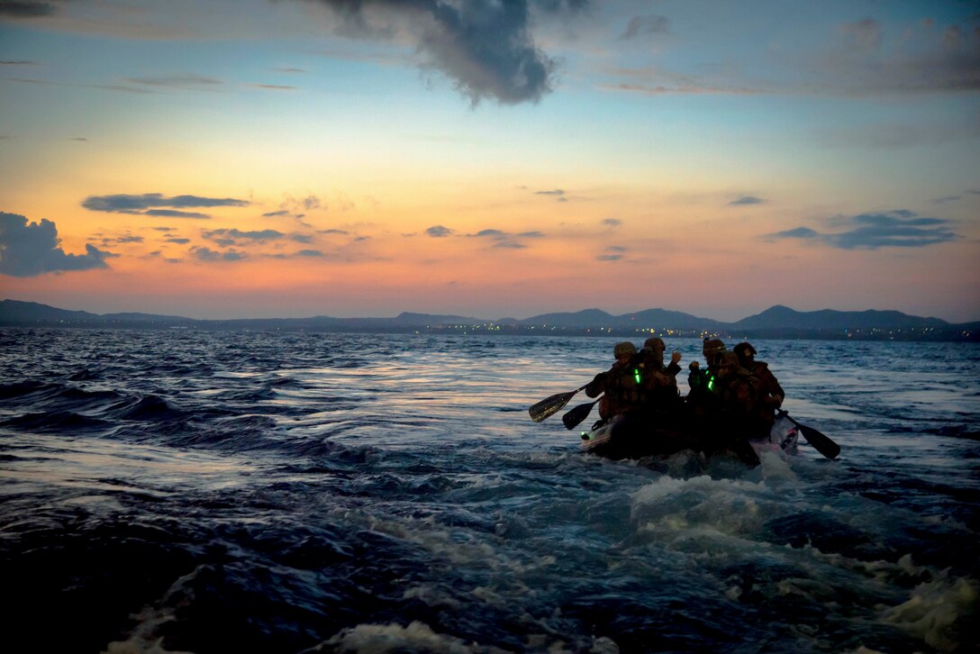 Marines sail in choppy waters under a sunlit sky.