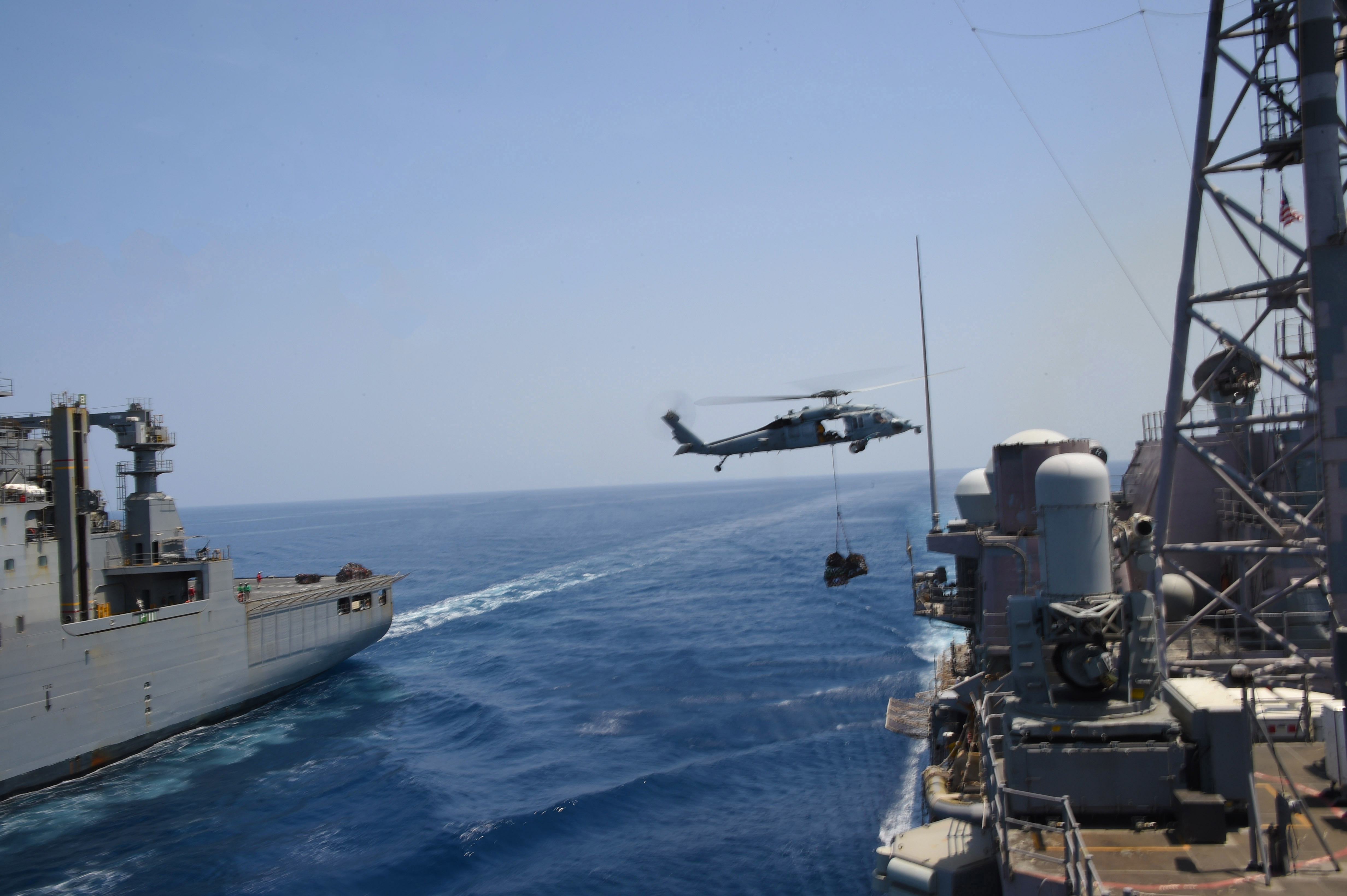 An MH-60S Sea Hawk helicopter transports cargo from the Military Sealift Command dry cargo and ammunition ship USNS Matthew Perry (T-AKE 9) to the guided-missile cruiser USS Philippine Sea (CG 58).