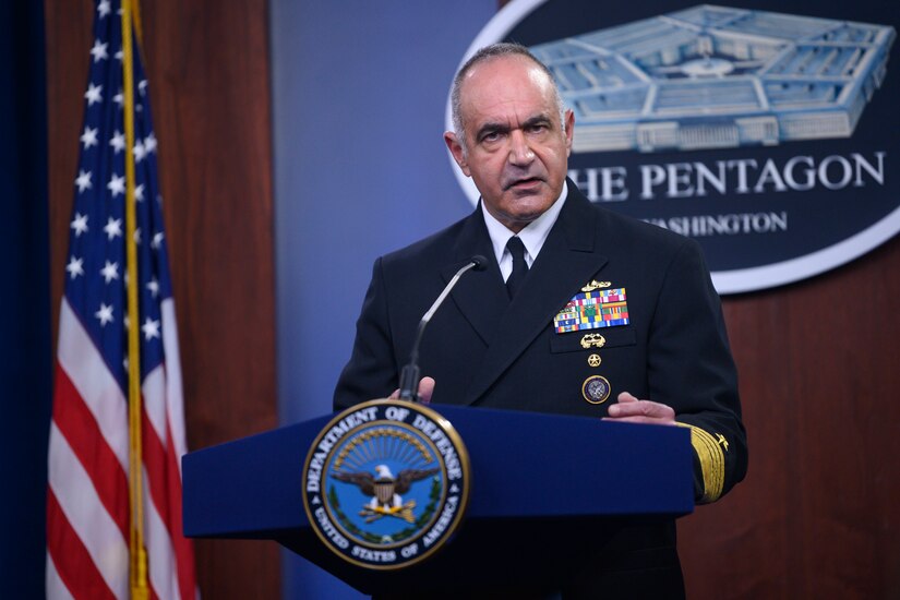 A Navy admiral speaks from a podium with a Pentagon sign hanging behind him.