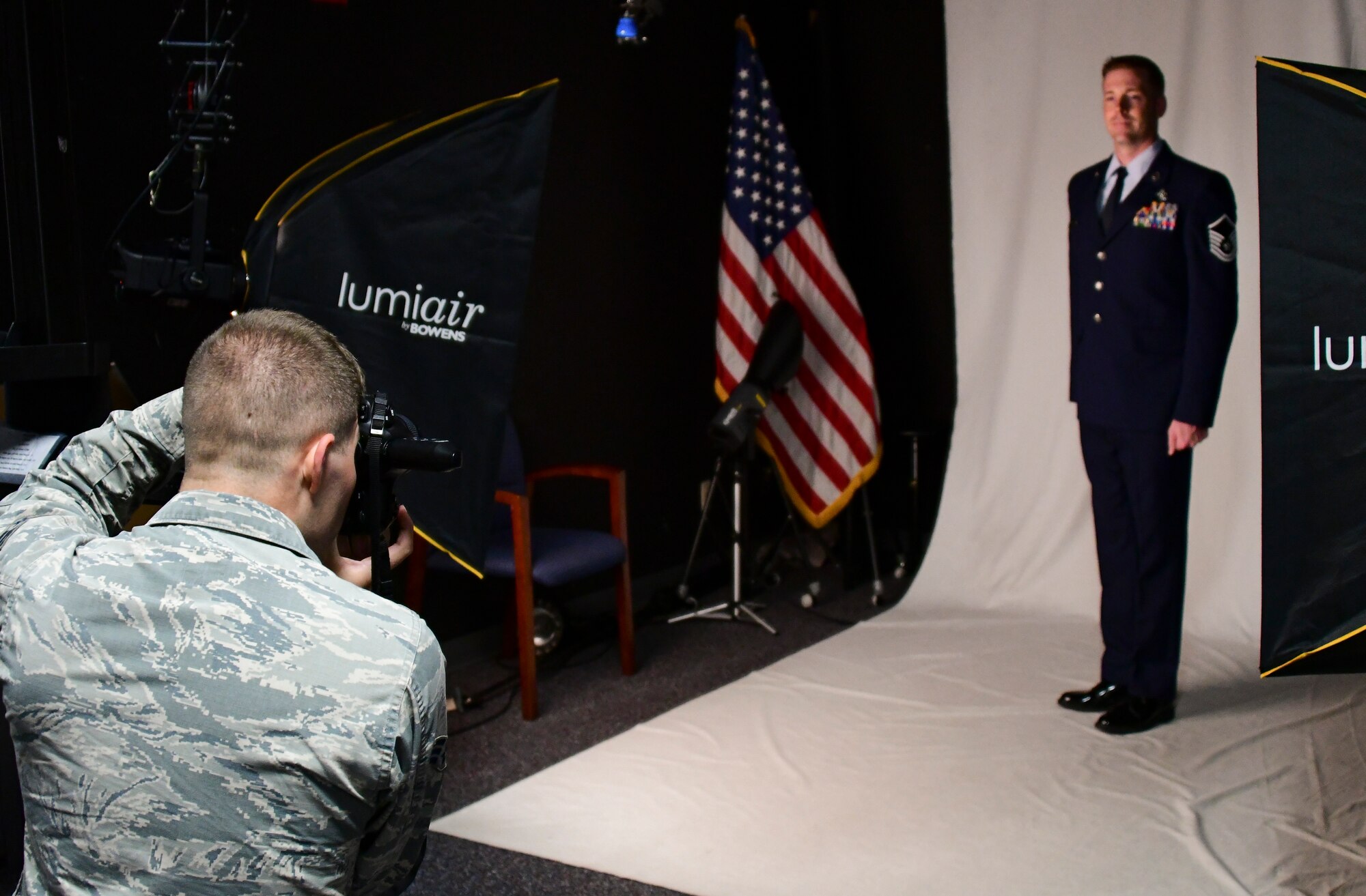 A photo of an airman taking a photo of another airman in the studio.