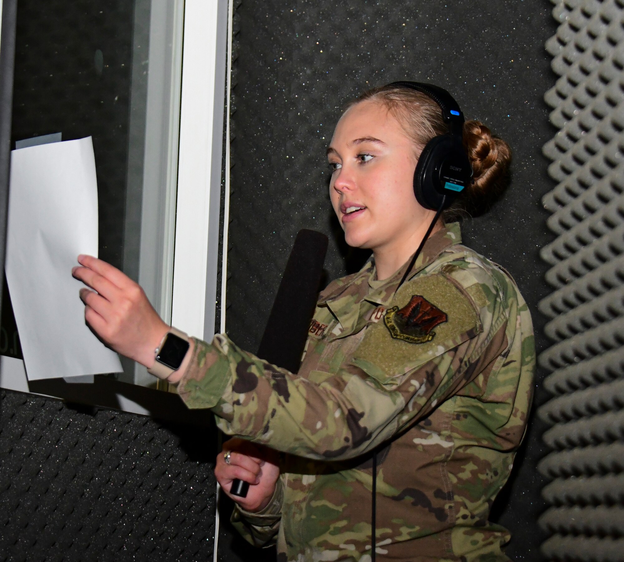A photo of an airman sitting in a sound booth to voice a script.