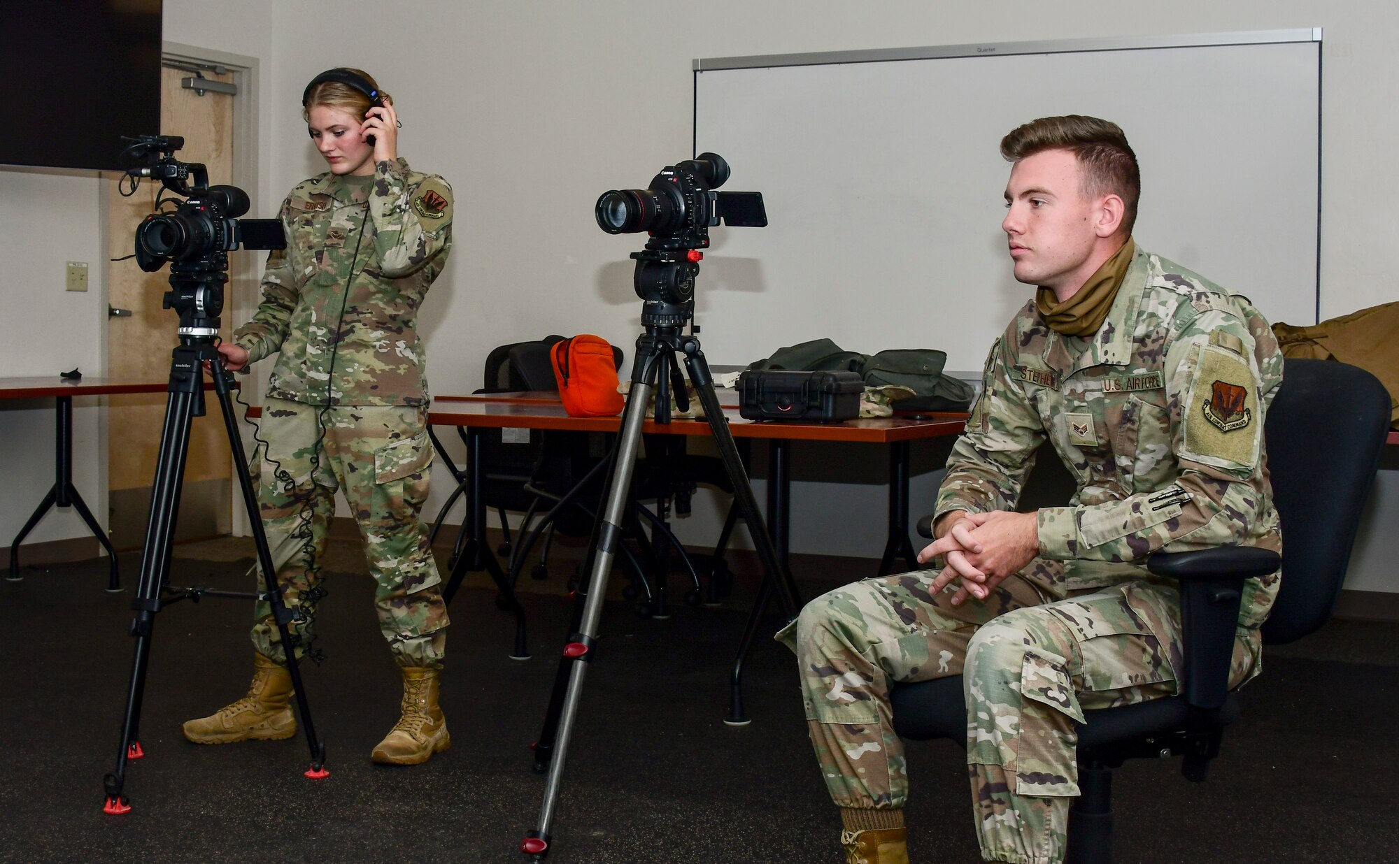 A photo of two airmen get ready to interview their subject for a story.