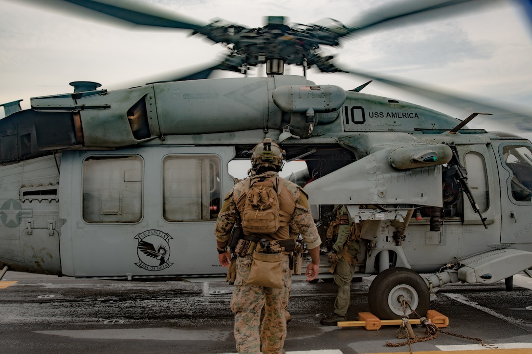 U.S. Marines get on an MH-60S Sea Hawk helicopter to provide aerial security during a visit, board, search, and seizure mission, aboard amphibious assault ship USS America (LHA 6), Aug. 26.