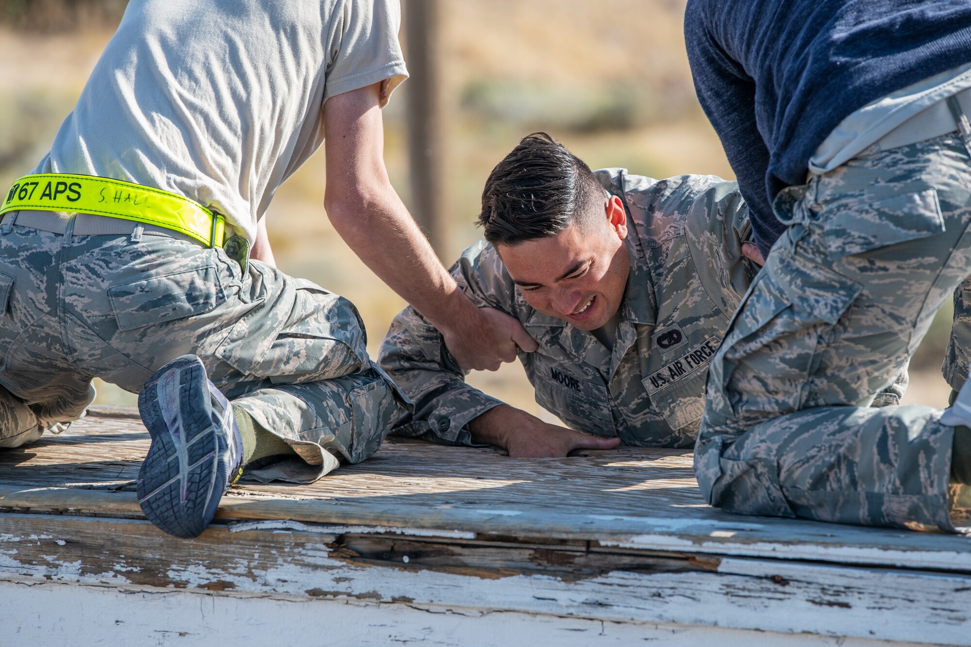 U.S. Air Force Senior Airman Hollan Moore, a reservist in the 419th Fighter Wing, pulls himself up with the help of fellow Airmen during an obstacle course