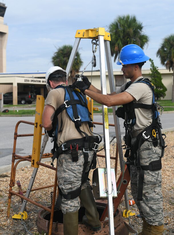 U.S. Air Force Airman 1st Class Emmanual Jackson-Willson, cable antenna systems technician with the 85th Engineering Installation Squadron assigned to Keesler Air Force Base, Mississippi, hooks the back of Staff Sgt. Jesse Laclair, cable antenna systems technician with the 85th EIS, as he prepares to go underground at Tyndall Air Force Base, Florida, Aug. 28, 2020. Laclair assisted in the process of modernizing Tyndall’s communication infrastructure. (U.S. Air Force photo by Airman Anabel Del Valle)