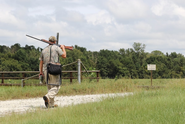 Man walks with rifle over his shoulder