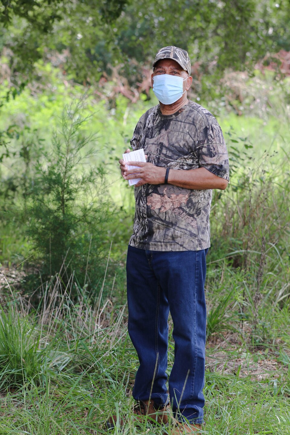 Man stands in a field and smiles at the camera