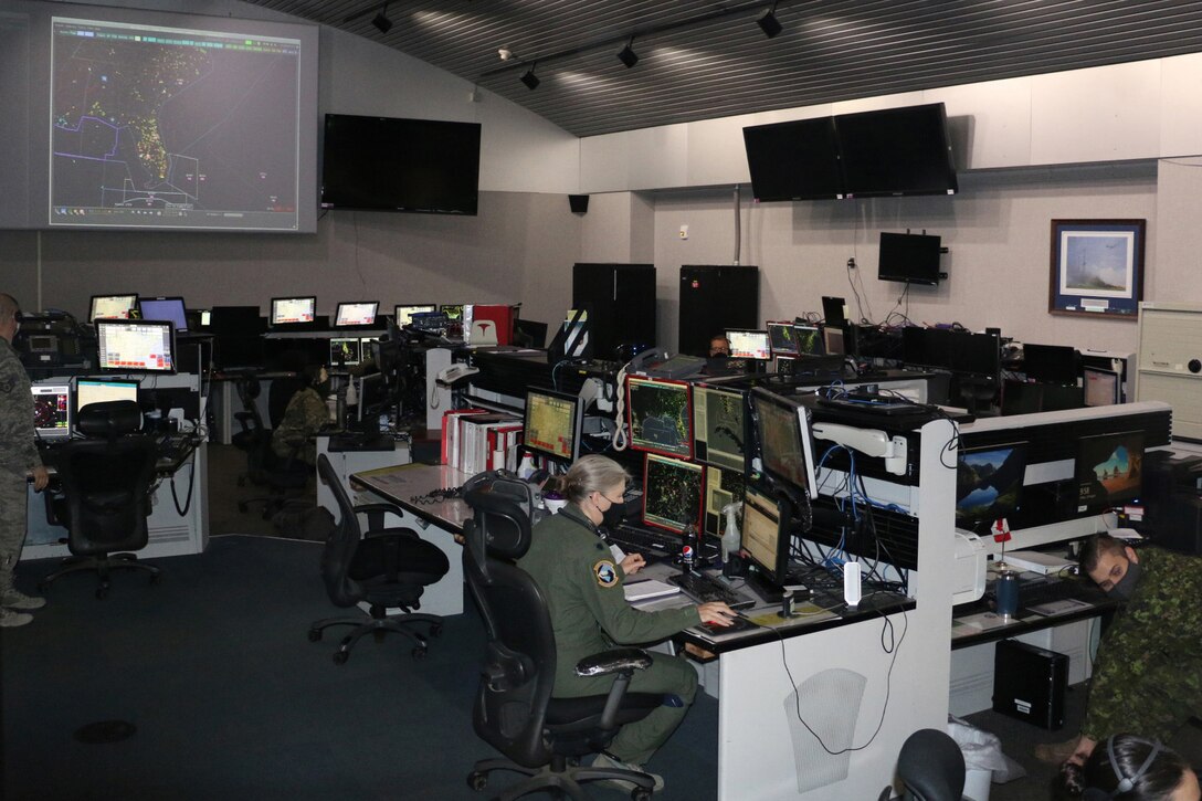 Socially distanced airmen working in a room with many computers.
