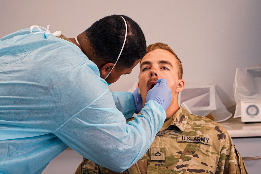 A soldier conducting a COVID-19 test on another soldier.