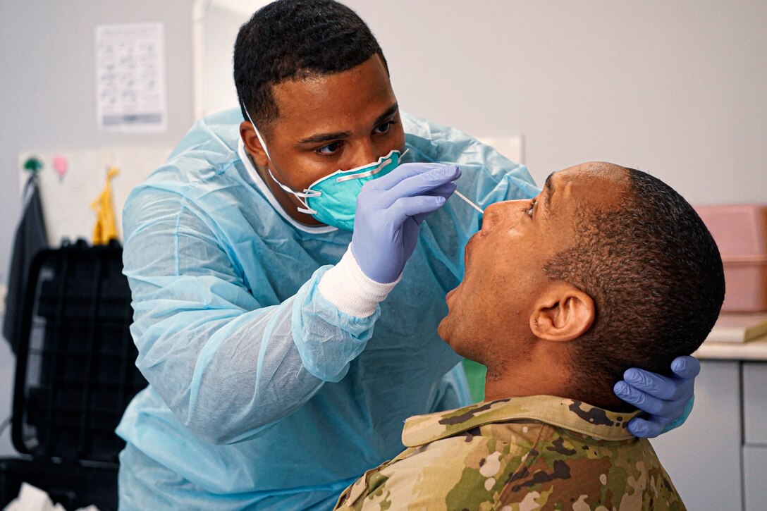 A soldier conducting a COVID-19 test on another soldier.