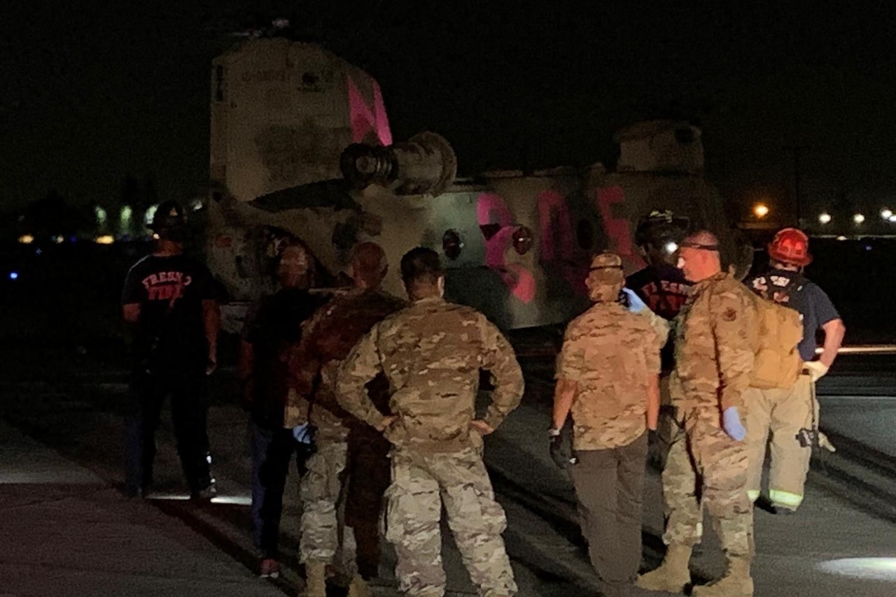 Men stand behind a helicopter.