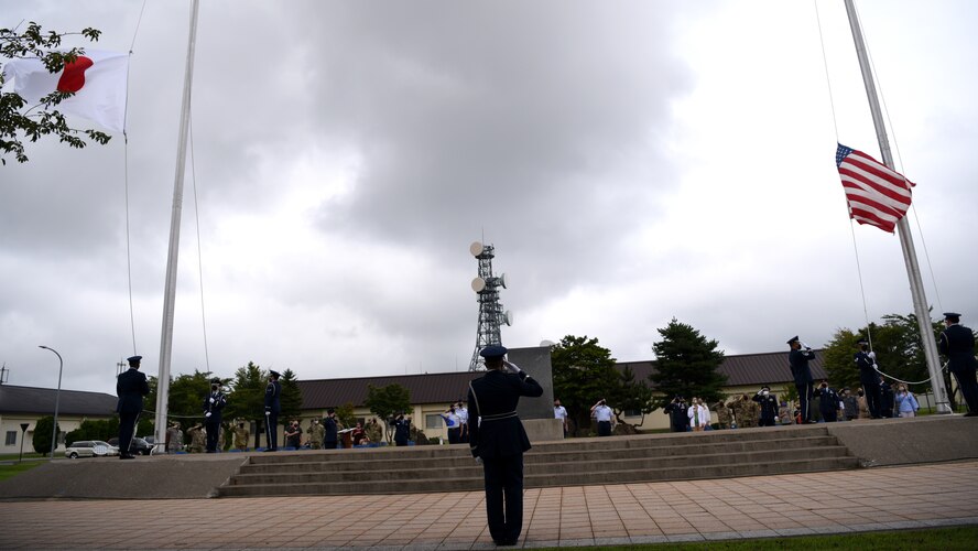Individuals in uniform participate in an outdoor ceremony