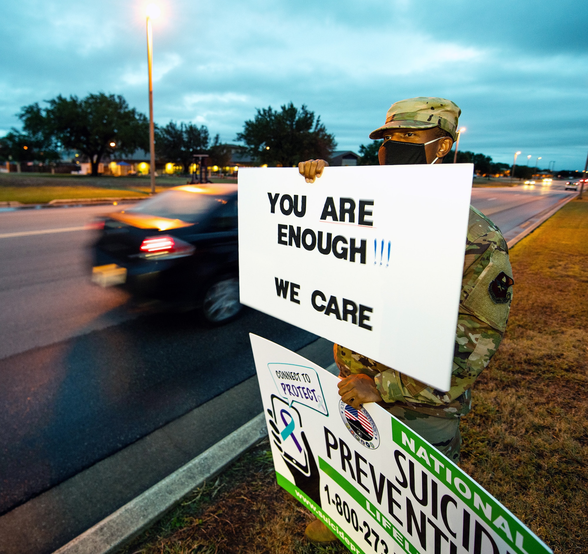 U.S. Air Force Tech. Sgt. Aaron Gibson, 737th Training Group military training consult training NCOIC, holds signs in support of the We Care Day event at Joint Base San Antonio-Lackland Sept. 10.