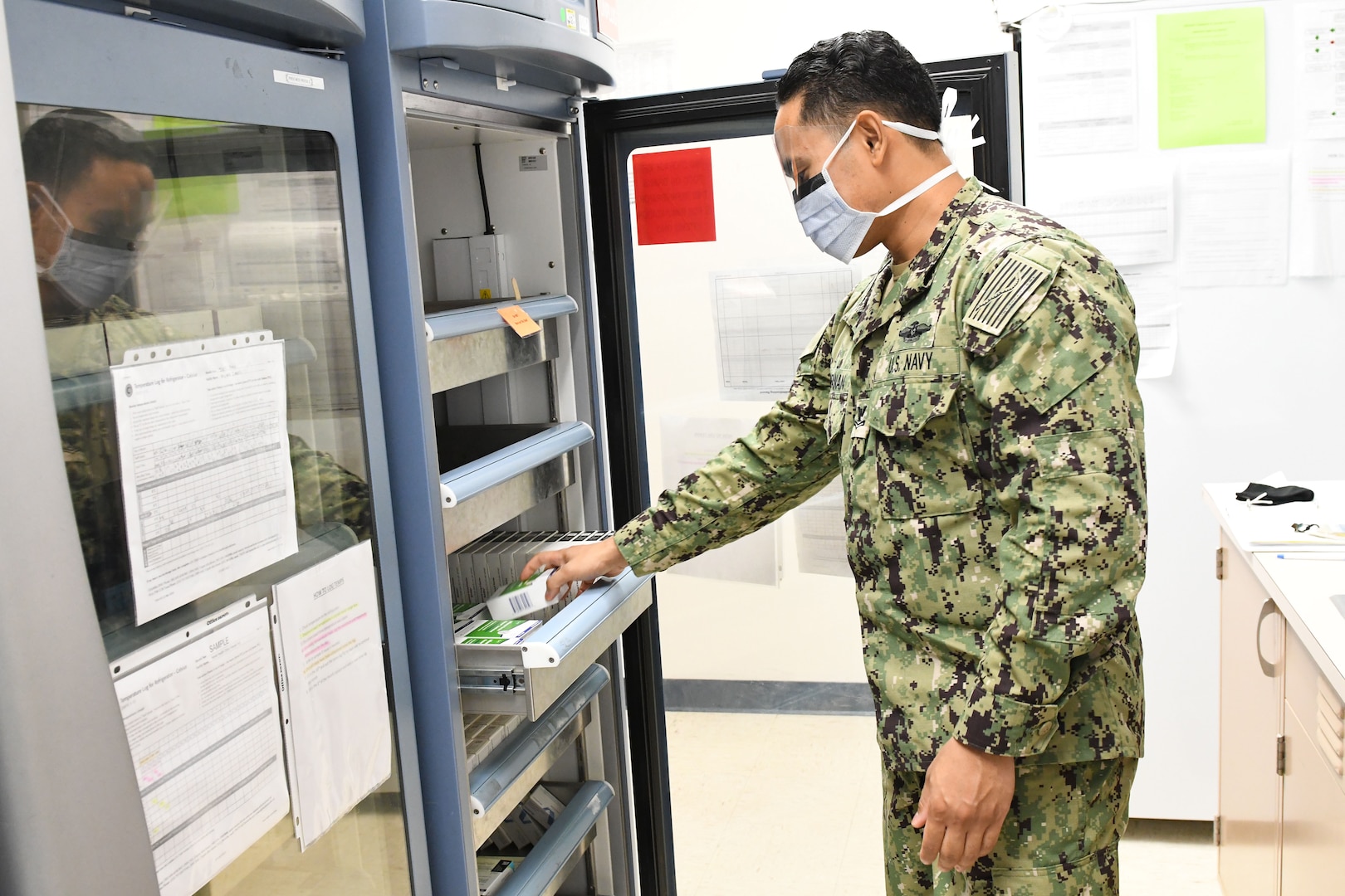 Sailor opens drawer in vaccine refrigerator.