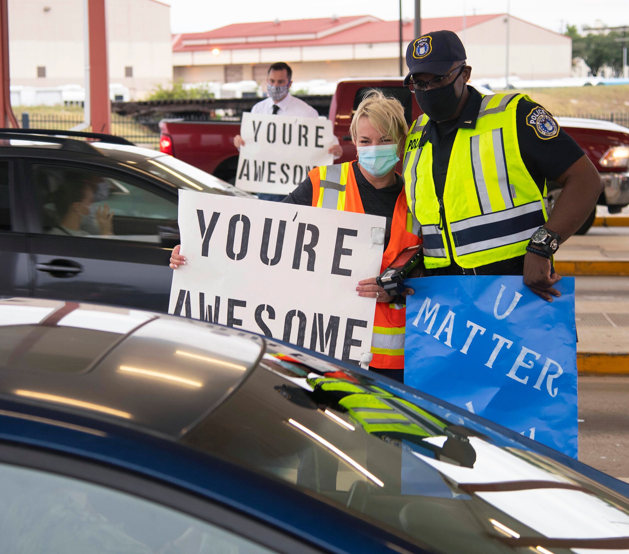 Carol Schmidt and Air Force Police Officer Lt. Steven B. Dews, both with the 502nd Security Forces Squadron, greet personnel entering the base while holding signs with positive messages in honor of World Suicide Prevention Day at the Walters Street Entry Control Point at Joint Base San Antonio-Fort Sam Houston Sept. 10.
