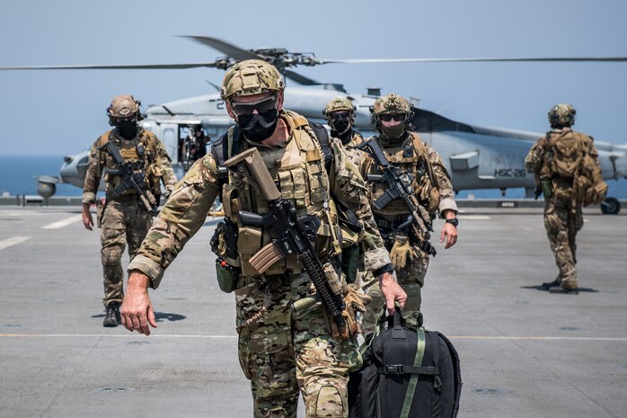 Explosive ordnance disposal technicians, assigned to Commander, Task Force (CTF) 56, prepare to board an MH-60S Sea Hawk helicopter, attached to Helicopter Sea Combat Squadron (HSC) 26, after conducting fast-rope training on the expeditionary mobile base USS Lewis B. Puller (ESB 3) in the Arabian Gulf.