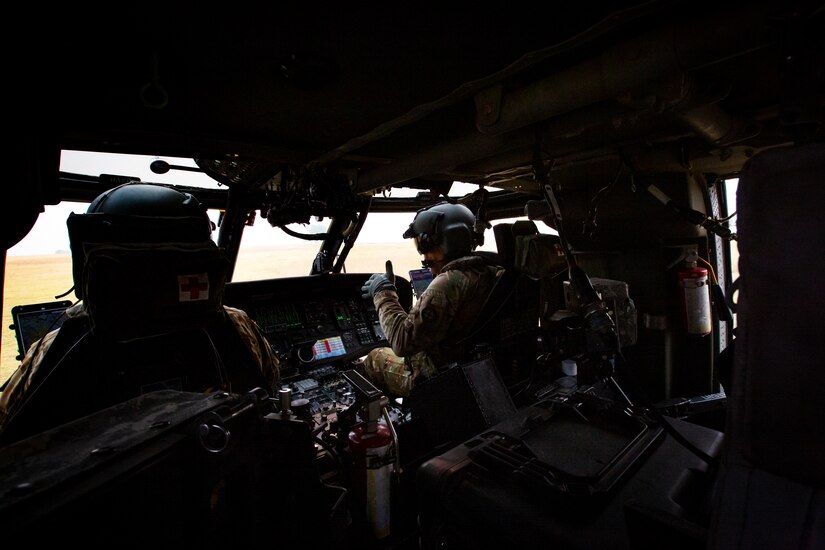 Two Black Hawk helicopter pilots speak to one another in the cockpit of their helicopter during water drop training in California.