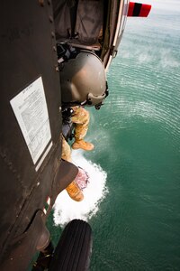 A solder looks out the side of a Black Hawk helicopter during water drop training, while they hover over Folsom Lake.