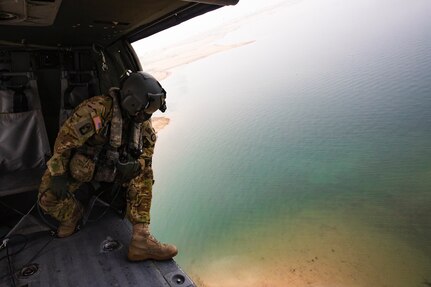 A soldier looks out from a Black Hawk helicopter during water drop training as they hover over Folsom Lake.