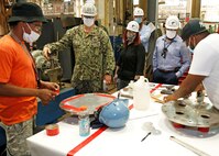 Norfolk Naval Shipyard (NNSY) Executive Development Program (EDP) Cadre 9 team members General Arrangements Branch (Code 254) Naval Architect Rachel Yarasavich, Code 105.2 Radiological Engineer Sasha Norfleet, and Code 361 Nuclear Zone Manager Aaron Jarman toured the production shops with Code 300 Operations Officers Capt. Michael Oberdorf to see the daily operations of the mechanics.