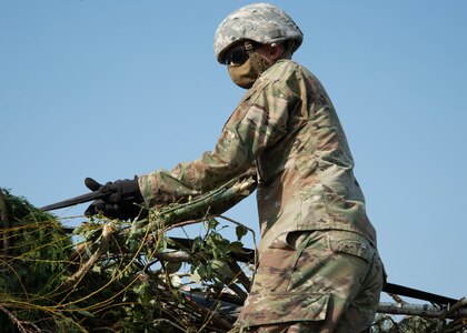 A Utah National Guard Soldier ties down tree debris on the back of a flat-bed trailer.