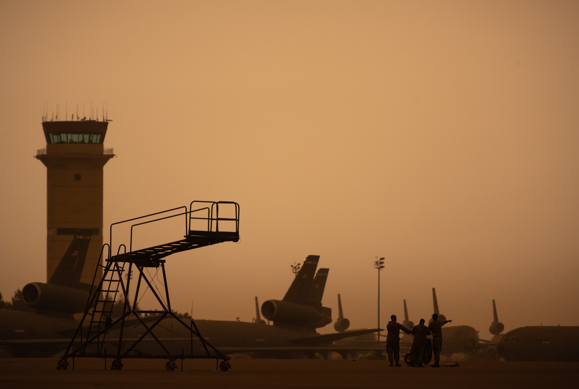 Airmen on the flight line with a smokey, yellowish sky.