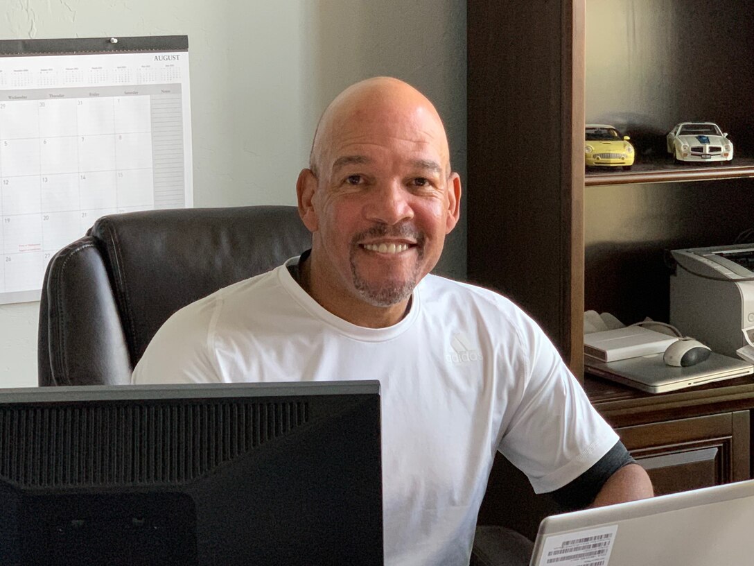 Photo of man in white shirt sitting at a desk behind a computer