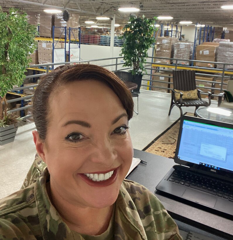 Female wearing her Air Force uniform is working in a warehouse with a lot of pallets