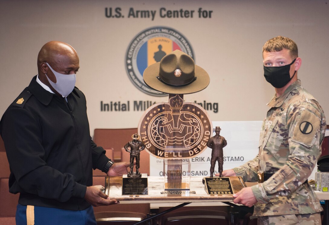 U.S. Army Staff Sgt. Erik A. Rostamo, (right), receives the Drill Sergeant of the Year award from Command Sgt. Maj. Edward Mitchell, Center for Initial Military Training, Sept. 10, 2020, at Fort Eustis, Virginia. The DSOY’s main role is to continuously review training guidance and regulations in order to mentor Army drill sergeants on lessons learned, training trends, and best courses of actions. (U.S. Air Force photo by Staff Sgt. Joshua Magbanua)