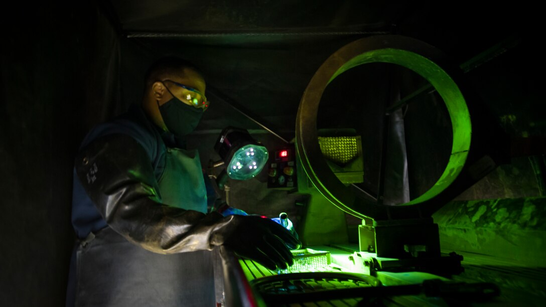 Tech. Sgt. Corey Nichols, a non-destructive inspection technician with the 177th Fighter Wing, Atlantic City International Airport, New Jersey, inspects aircraft parts utilizing a UV light at Edwards Air Force Base, California, July 24. (Air Force photo by Giancarlo Casem)