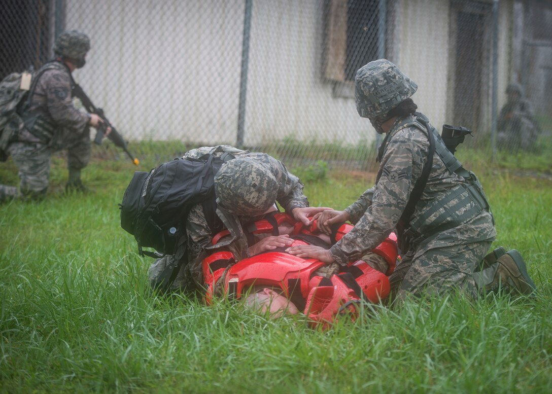 An airman takes down a simulated adversary while another airman helps.