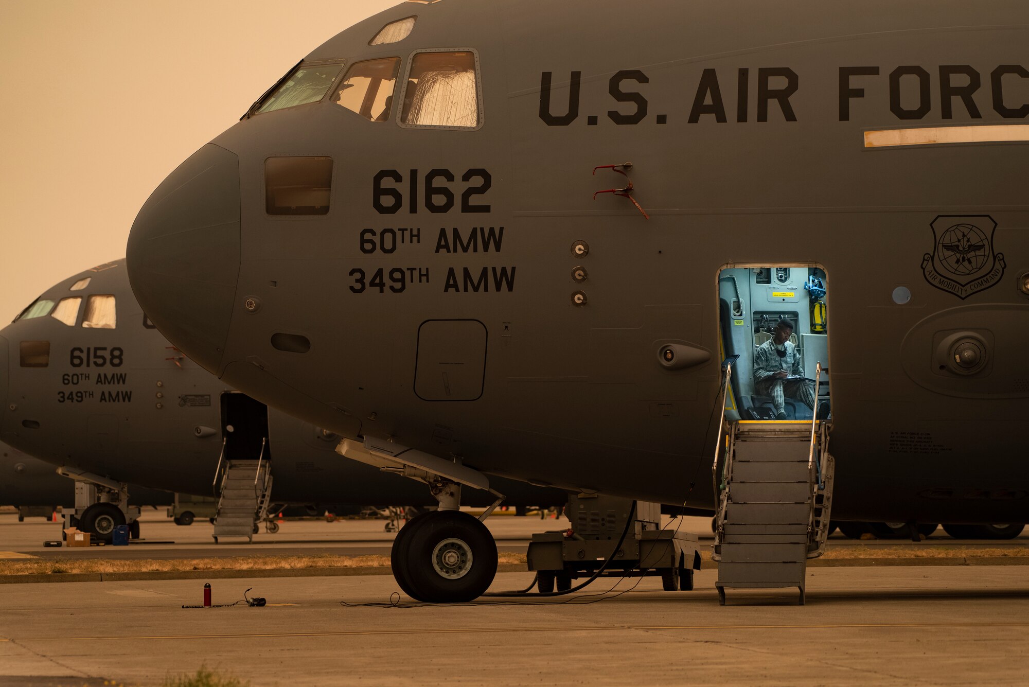 U.S. Air Force Airman 1st Class Jasper Walker, 860th Aircraft Maintenance Squadron integrated flight system control journeyman, looks over paperwork while inside a C-17 Globemaster III Sept. 9, 2020 at Travis Air Force Base, California. Wildfires across California propelled smoke and ash into the troposphere, impacting air quality. (U.S. Air Force photo by Heide Couch)