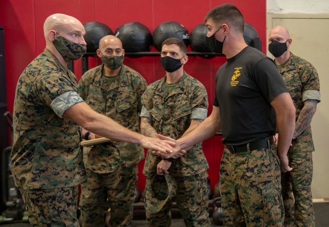 The 19th Sergeant Major of the Marine Corps, Sgt. Maj. Troy E. Black, presents a coin to SSgt. Mattheau Ross, a Force Fitness Instructor Trainer at The Basic School (TBS) Fitness Center, Marine Corps Base Quantico, V.A., Sept. 10, 2020. The purpose of the visit was to look at the Officer Candidate training facilities and speak to the instructors responsible for facilitating countless hours of training. The Fitness Center housed at TBS includes the only Force Fitness Instructor certifying course in the Marine Corps. (U.S. Marine Corps photo by Sgt. Victoria Ross)